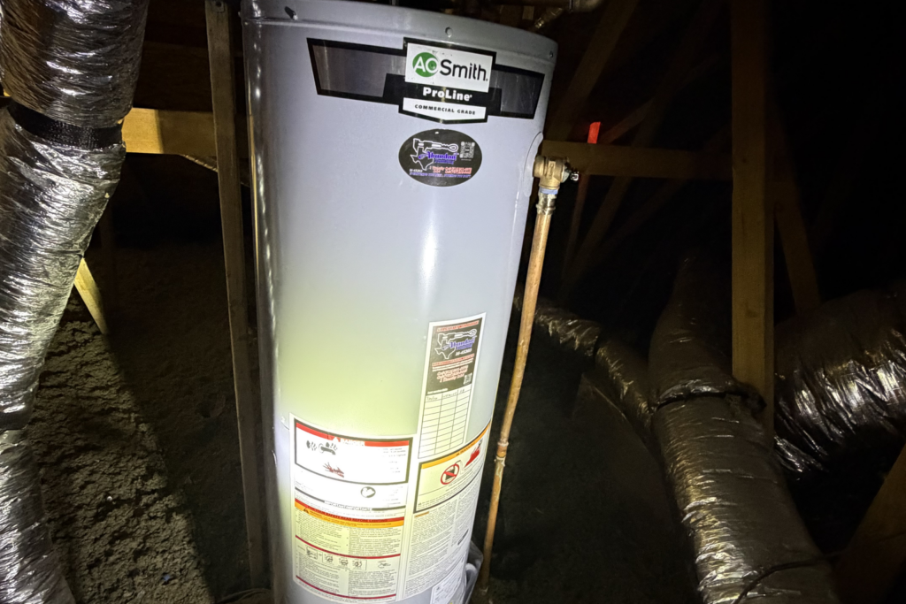 Newly installed A.O. Smith ProLine tank water heater in an attic, with the temperature and pressure valve, copper takeoff and yellow gas connector